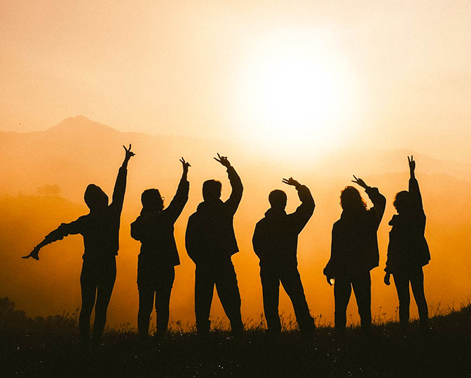 Silhouette of students celebrating outside.